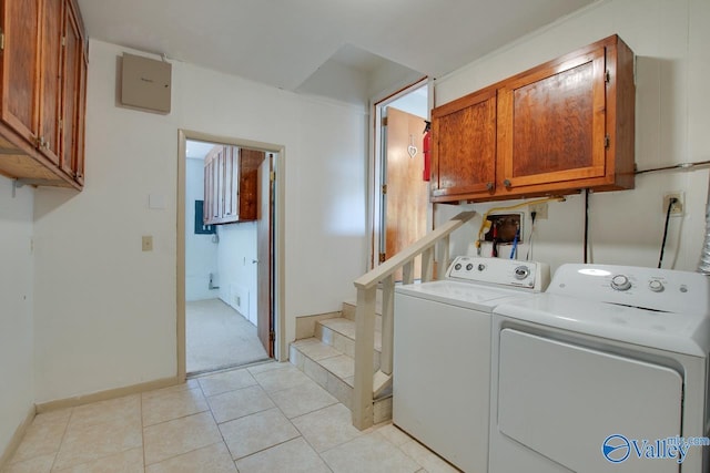 laundry room with light tile patterned floors, washer and clothes dryer, cabinet space, and baseboards