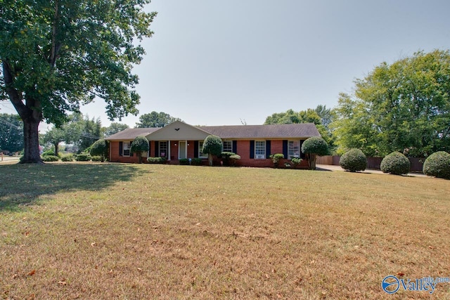 ranch-style home featuring fence and a front lawn