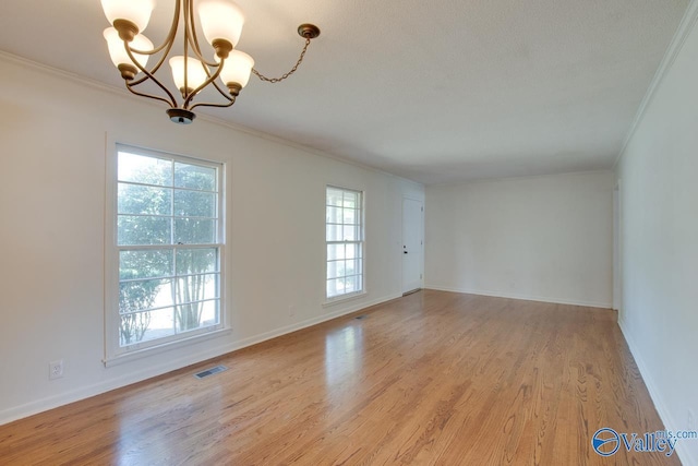 spare room featuring baseboards, light wood-style flooring, visible vents, and crown molding