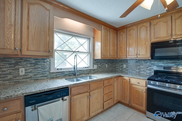 kitchen with appliances with stainless steel finishes, light tile patterned flooring, a sink, and light stone countertops