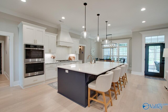 8076 Goose Ridge Dr, Owens Cross Roads, AL 35763 - kitchen with stainless steel appliances, premium range hood, light countertops, tasteful backsplash, and white cabinets