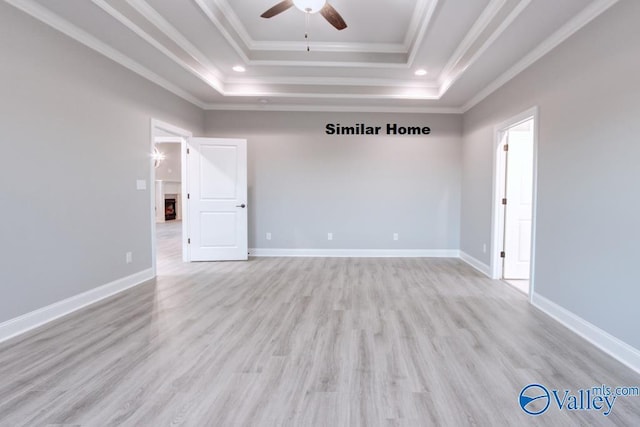 spare room with ornamental molding, light hardwood / wood-style flooring, ceiling fan, and a tray ceiling