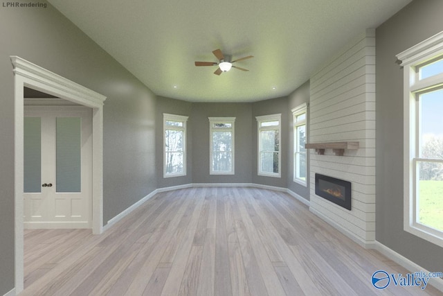 unfurnished living room with ceiling fan, a healthy amount of sunlight, a fireplace, and light wood-type flooring