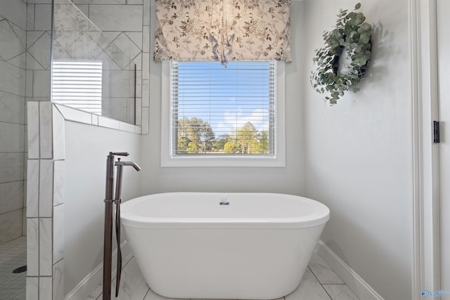 bathroom with a freestanding bath, a tile shower, marble finish floor, and baseboards