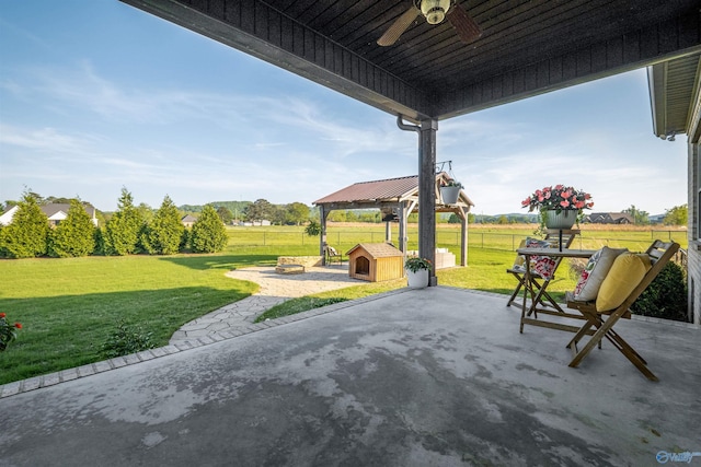 view of patio / terrace featuring a storage unit, a gazebo, fence, ceiling fan, and an outdoor structure
