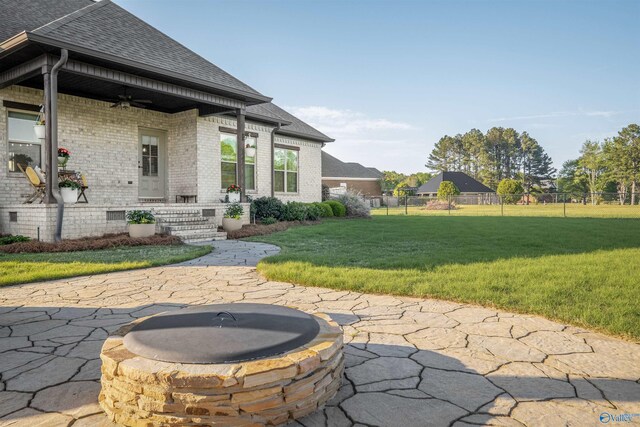 view of patio featuring a fire pit, fence, and ceiling fan