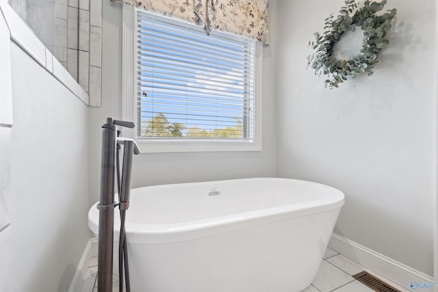 bathroom featuring a soaking tub, baseboards, and visible vents