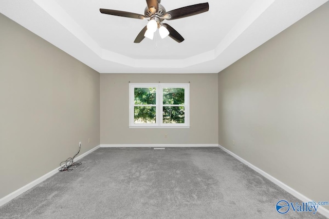 carpeted spare room featuring ceiling fan and a raised ceiling