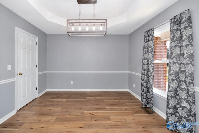 interior space with hardwood / wood-style floors, an inviting chandelier, and a tray ceiling