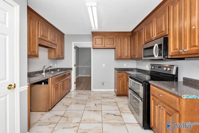 kitchen with sink, stainless steel appliances, light hardwood / wood-style floors, and dark stone countertops