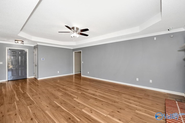 empty room featuring hardwood / wood-style floors, crown molding, ceiling fan, and a tray ceiling