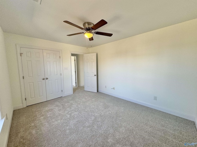 unfurnished bedroom with light carpet, ceiling fan, a closet, and baseboards