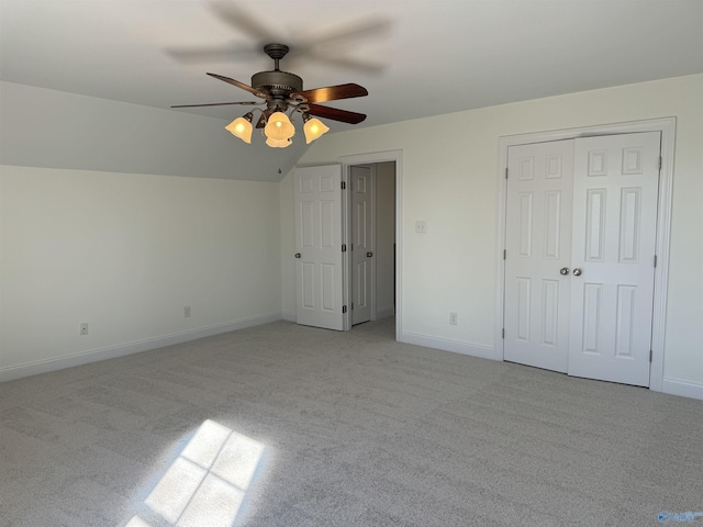 unfurnished bedroom featuring lofted ceiling, ceiling fan, light carpet, and baseboards