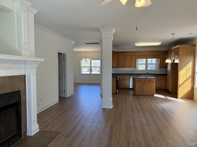 kitchen with a tiled fireplace, dark countertops, dark wood-style flooring, ornate columns, and a sink