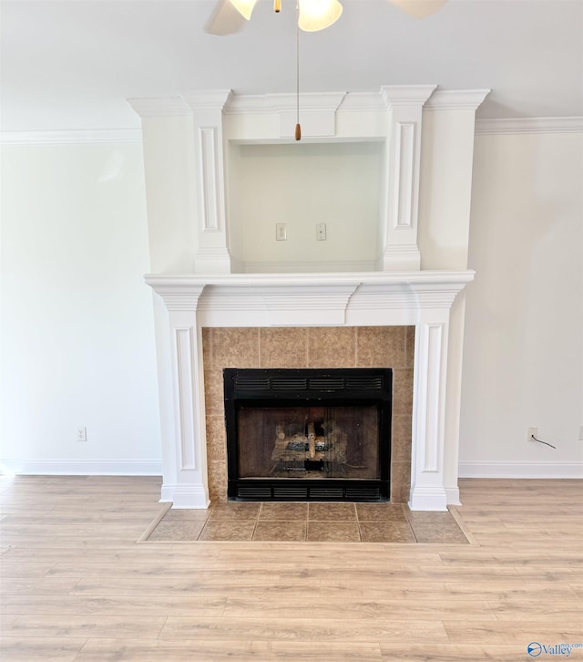 room details featuring ornamental molding, a tiled fireplace, and wood finished floors