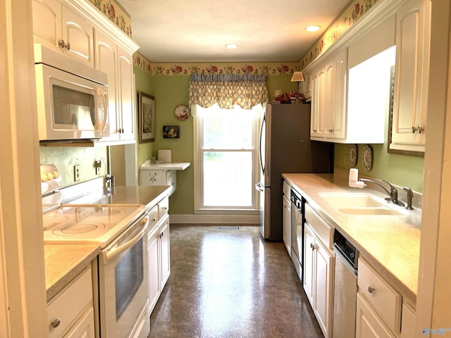 kitchen featuring baseboards, visible vents, appliances with stainless steel finishes, light countertops, and a sink