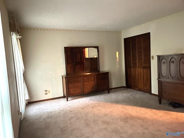 unfurnished bedroom featuring light carpet and baseboards