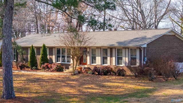 ranch-style home featuring roof with shingles and brick siding