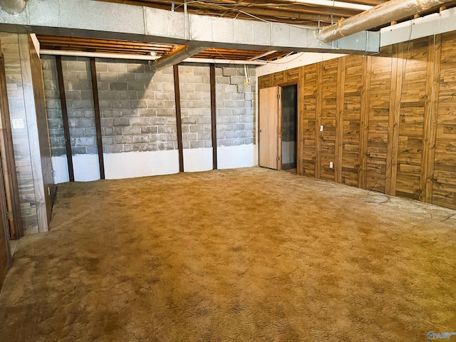 unfinished basement featuring concrete block wall and carpet
