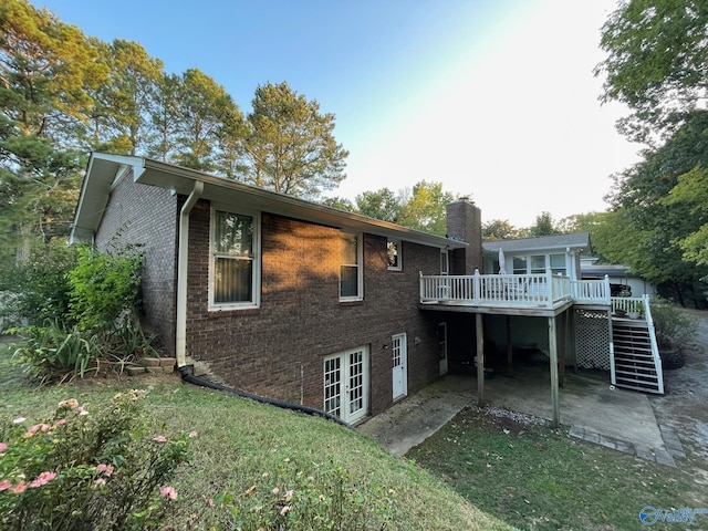 back of house with stairway, a chimney, brick siding, and a deck