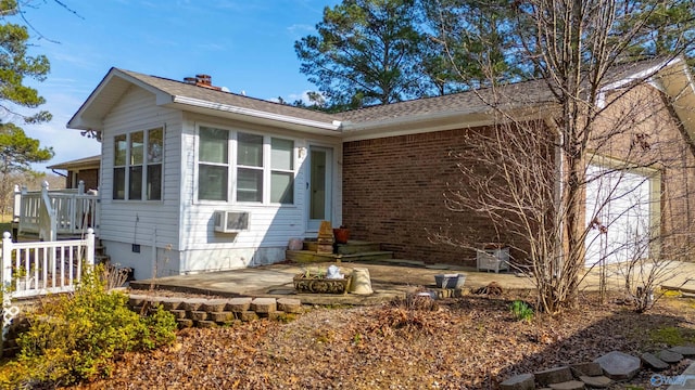 ranch-style house with entry steps, a wall mounted air conditioner, brick siding, a chimney, and a patio area