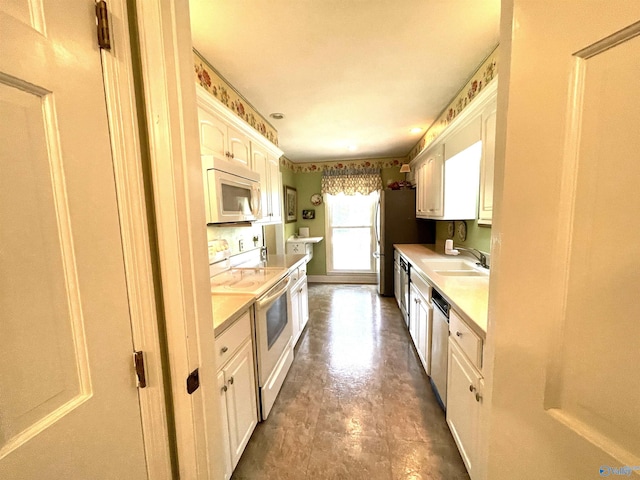 kitchen featuring white cabinets, dark tile patterned flooring, sink, and white appliances