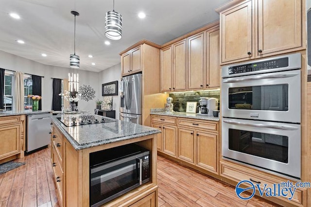 kitchen with pendant lighting, light hardwood / wood-style floors, light stone counters, and appliances with stainless steel finishes