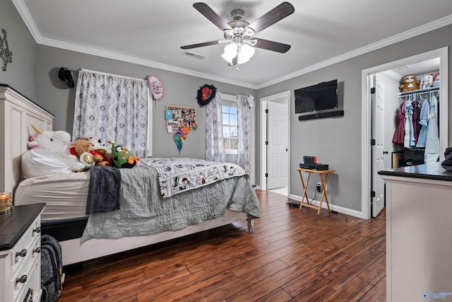 bedroom featuring a walk in closet, ceiling fan, dark hardwood / wood-style floors, ornamental molding, and a closet