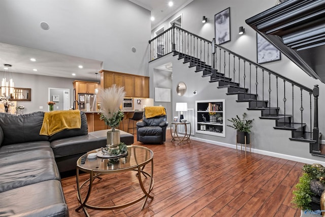 living room with a notable chandelier, wood-type flooring, and a towering ceiling