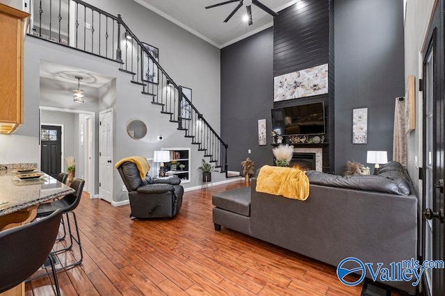 living room with a fireplace, light hardwood / wood-style flooring, ceiling fan, and ornamental molding