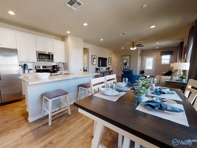 dining area with sink, ceiling fan, and light wood-type flooring