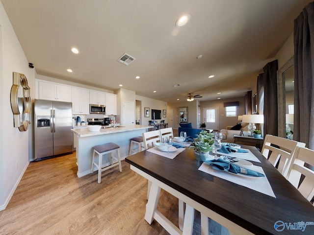 dining space with ceiling fan, sink, and light hardwood / wood-style floors