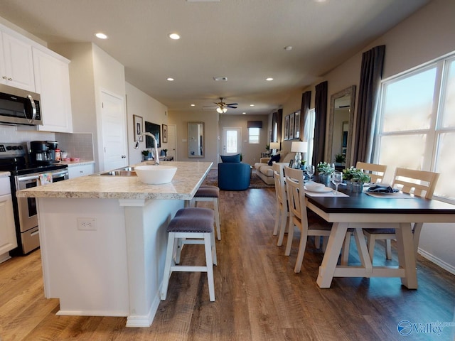 kitchen featuring hardwood / wood-style flooring, stainless steel appliances, sink, and a center island with sink