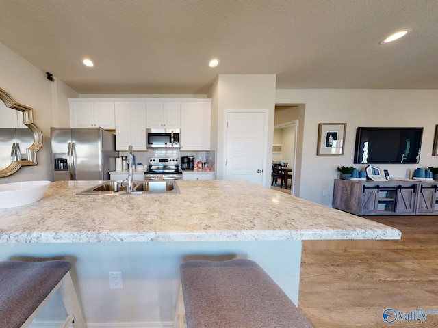 kitchen with white cabinetry, sink, backsplash, a kitchen breakfast bar, and stainless steel appliances