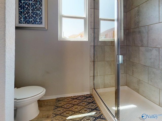 bathroom featuring toilet and a shower with door