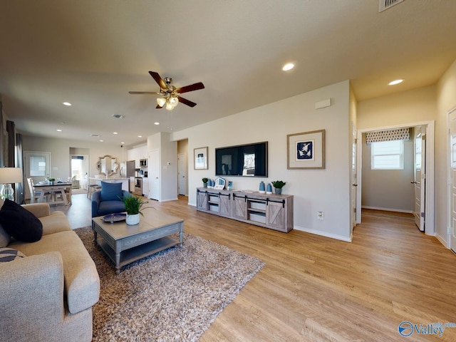 living room featuring light hardwood / wood-style flooring and ceiling fan