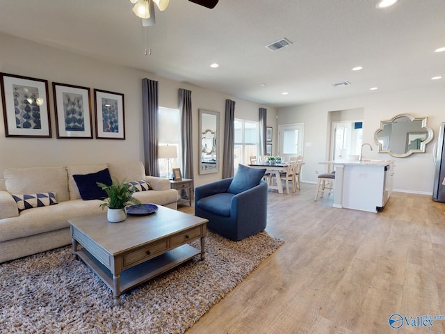 living room with ceiling fan, sink, and light hardwood / wood-style floors