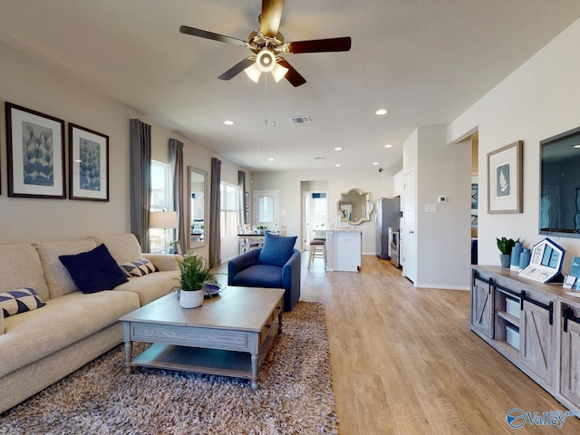 living room featuring sink, ceiling fan, and light wood-type flooring