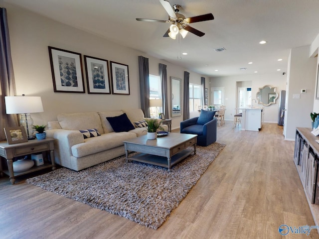 living room with ceiling fan, sink, and light hardwood / wood-style flooring