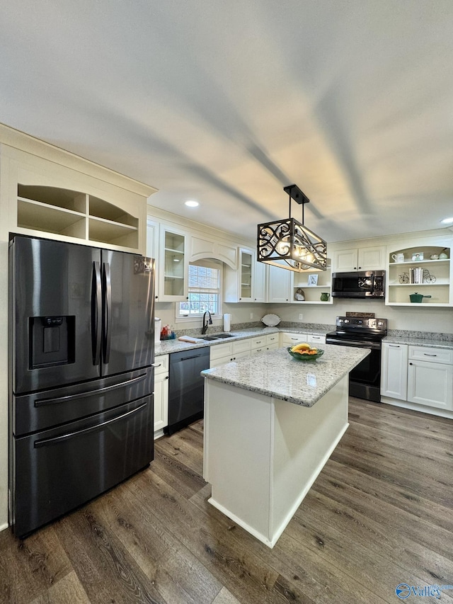 kitchen with a center island, white cabinets, hanging light fixtures, and black appliances