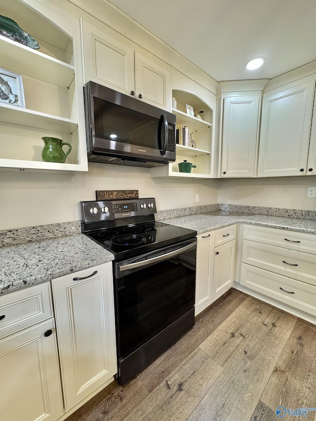 kitchen featuring white cabinets, light hardwood / wood-style floors, light stone countertops, and black / electric stove