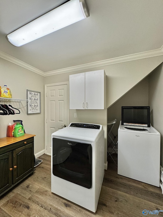 washroom featuring washing machine and dryer, cabinets, hardwood / wood-style floors, and ornamental molding