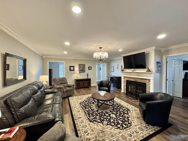 living room with hardwood / wood-style flooring, a chandelier, crown molding, and a brick fireplace