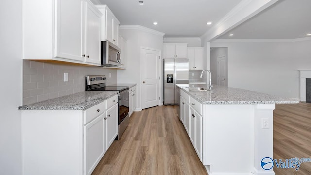 kitchen with sink, white cabinetry, stainless steel appliances, and a kitchen island with sink