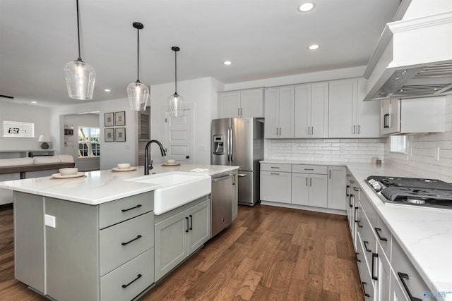 kitchen featuring pendant lighting, premium range hood, an island with sink, appliances with stainless steel finishes, and tasteful backsplash