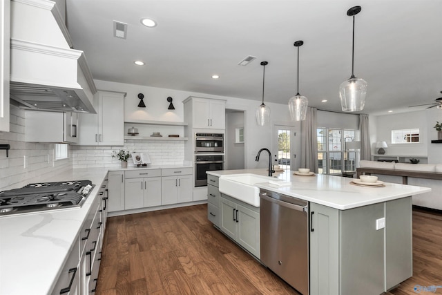 kitchen with sink, hanging light fixtures, tasteful backsplash, an island with sink, and appliances with stainless steel finishes