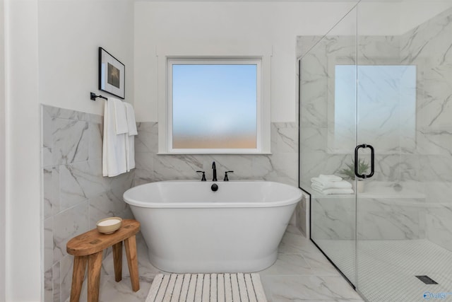 bathroom featuring shower with separate bathtub and tile walls