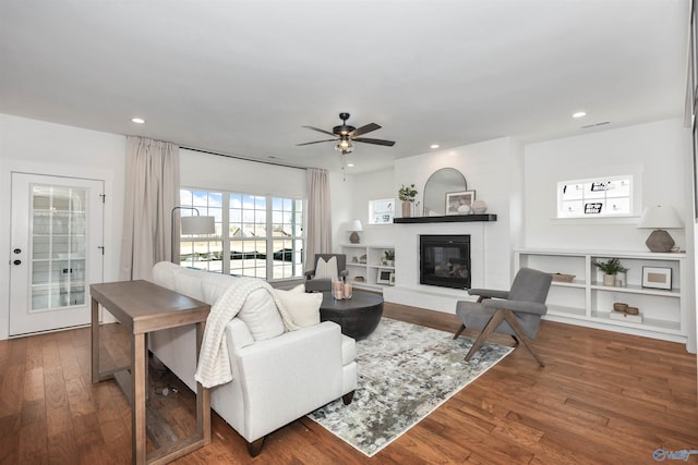 living room featuring hardwood / wood-style flooring, ceiling fan, and a fireplace