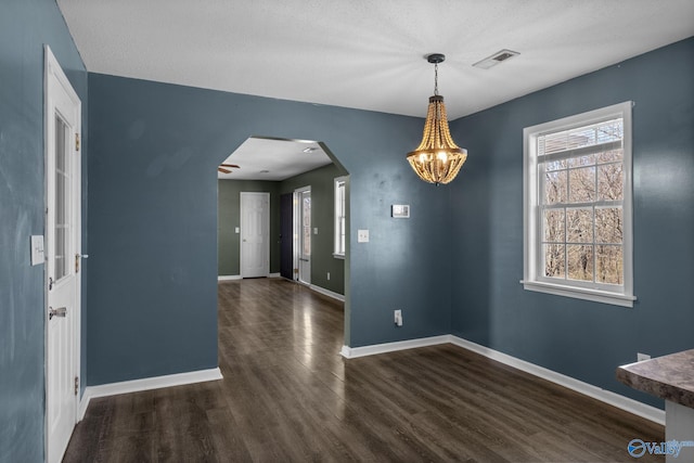 unfurnished dining area featuring dark wood-type flooring, arched walkways, visible vents, and baseboards