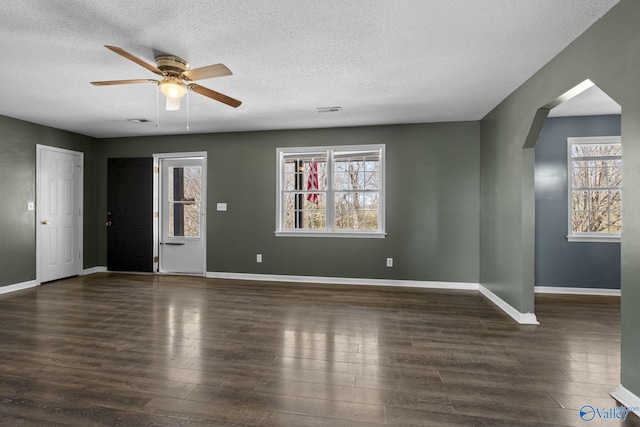 interior space featuring arched walkways, dark wood-style flooring, visible vents, and baseboards